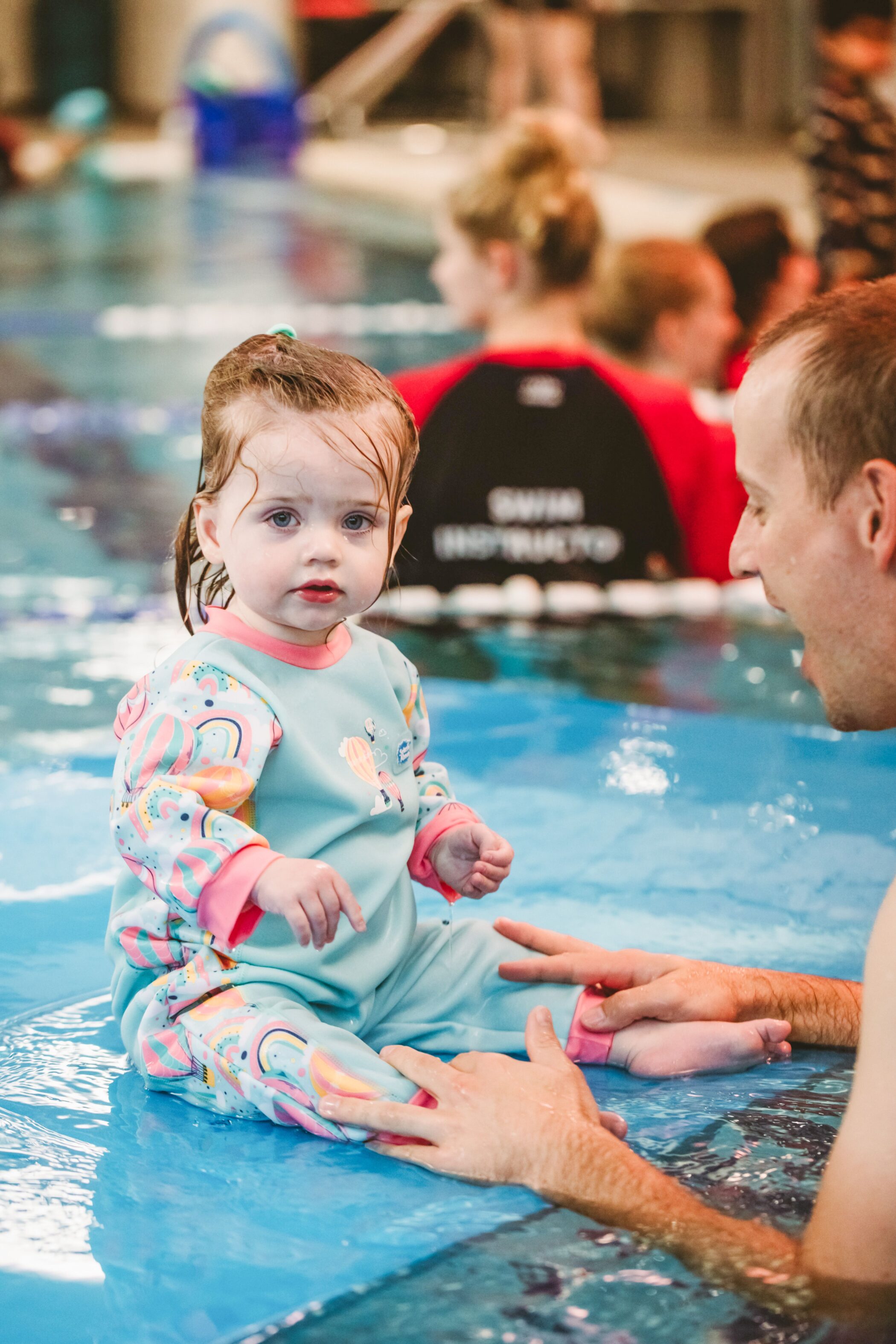 Toddler sitting poolside with a parent during a Pymble Swimming baby class