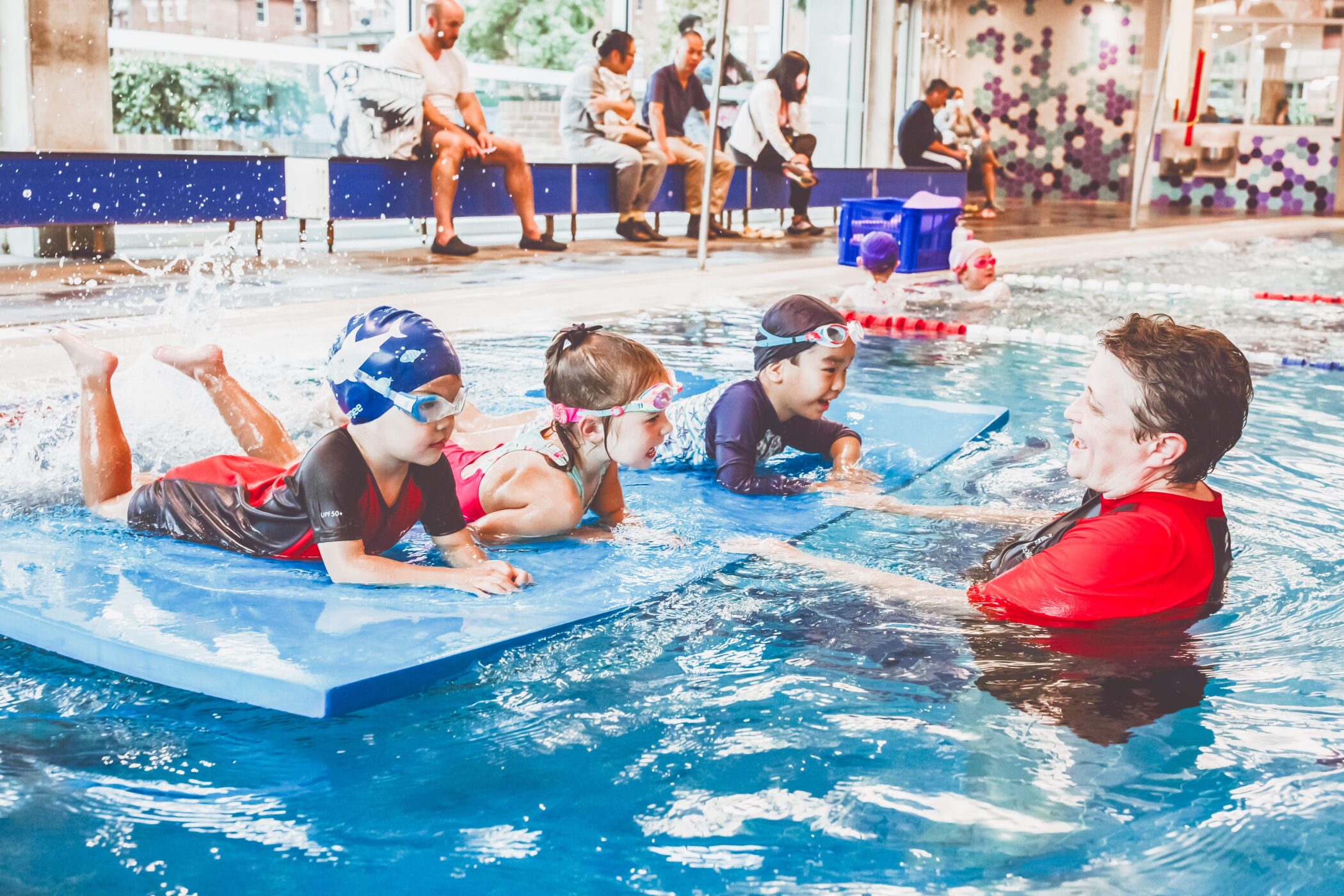 Pymble Swimming instructor guiding three children on kickboards during a group swim lesson