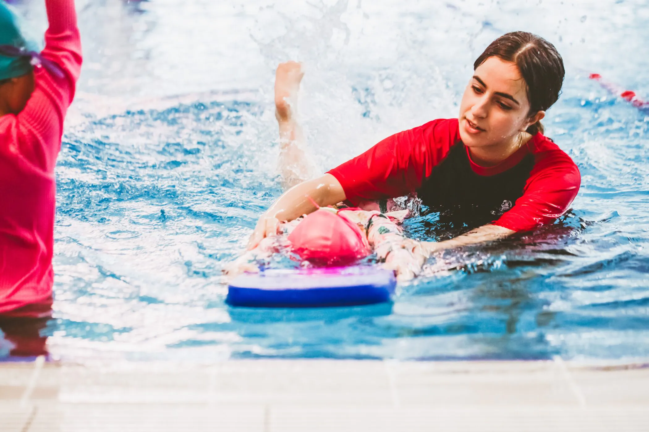Pymble Swimming instructor supporting a child kicking on a kickboard
