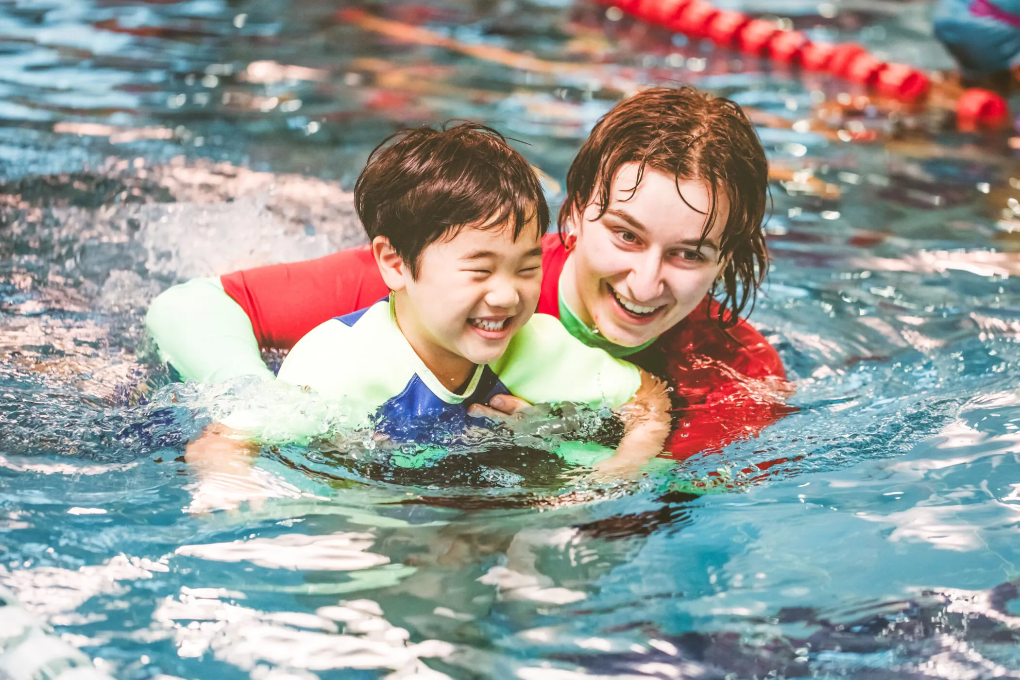 Pymble Swimming instructor supporting a smiling toddler during a learn-to-swim lesson
