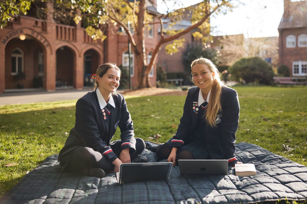 girls on grass with laptops